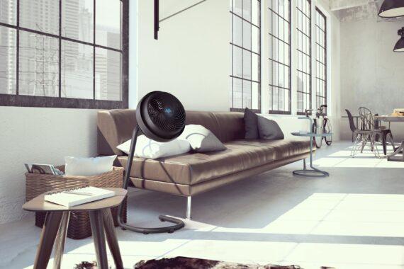 Lifestyle of a Black 783 large stand air circulator in an open spaced office by a lounge couch