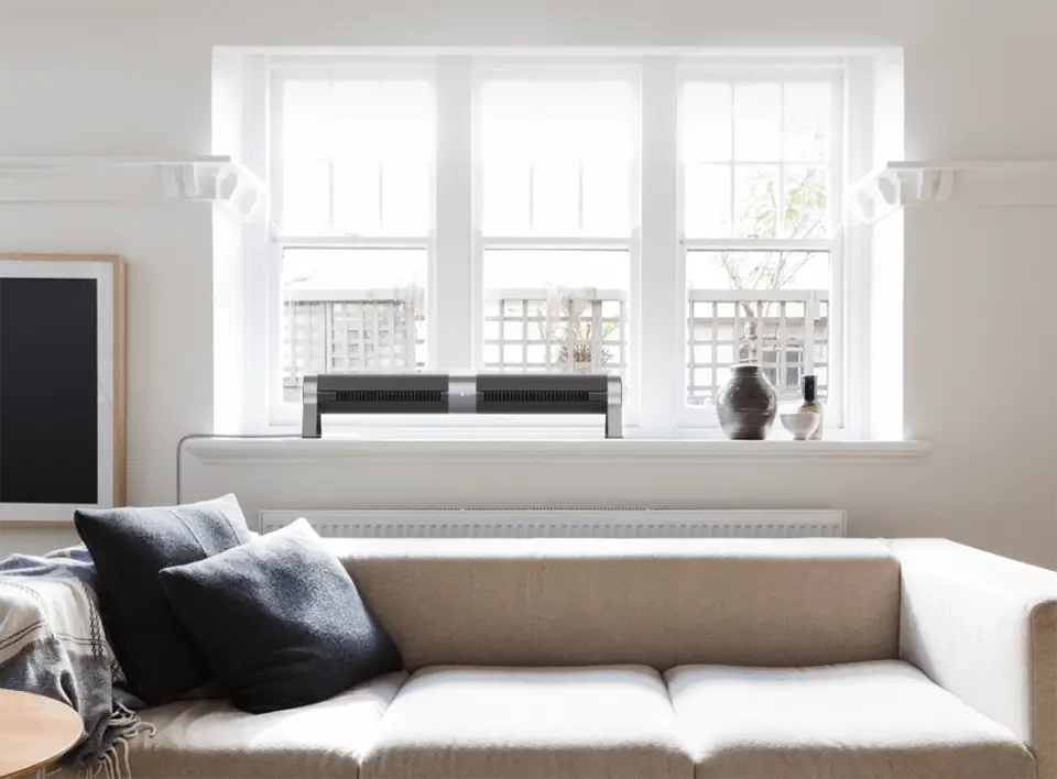 An Airbar 4 sitting on a window ledge in horizontal Airbar position, circulating air over a couch in a living room.