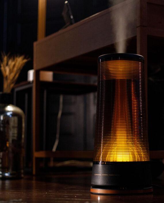 Lifestyle image of Vornado LUCERNA 3 Alchemy Ultrasonic Humidifier on a dark wood floor.