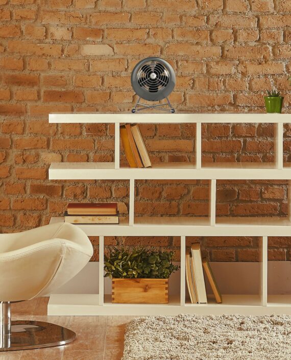 Lifestyle of a storm grey VFAN Mini Modern Vintage Air Circulator on an open shelf in a living room