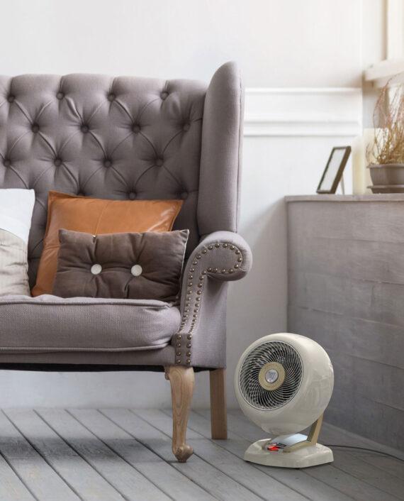 Lifestyle of a white Vheat Whole room vintage heater on the gray floor near a Mauve armchair